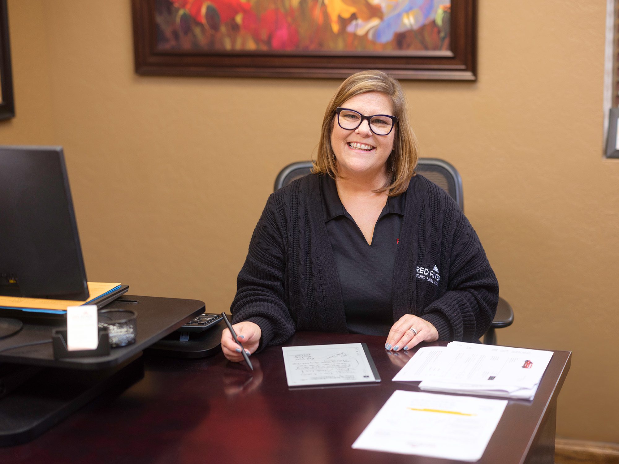 Red River Employee at desk with paperwork smiling